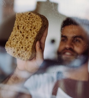 Huishoudhulp Germani maakt de ramen proper in de woonkamer Huishoudhulp Germani maakt de ramen proper in de woonkamer